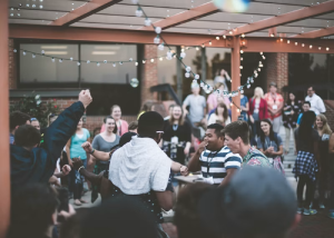 Friends socializing at an outdoor evening gathering with string lights